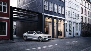 Volvo S60 color plata saliendo de Garage a calle color gris, presumiblemente Londres